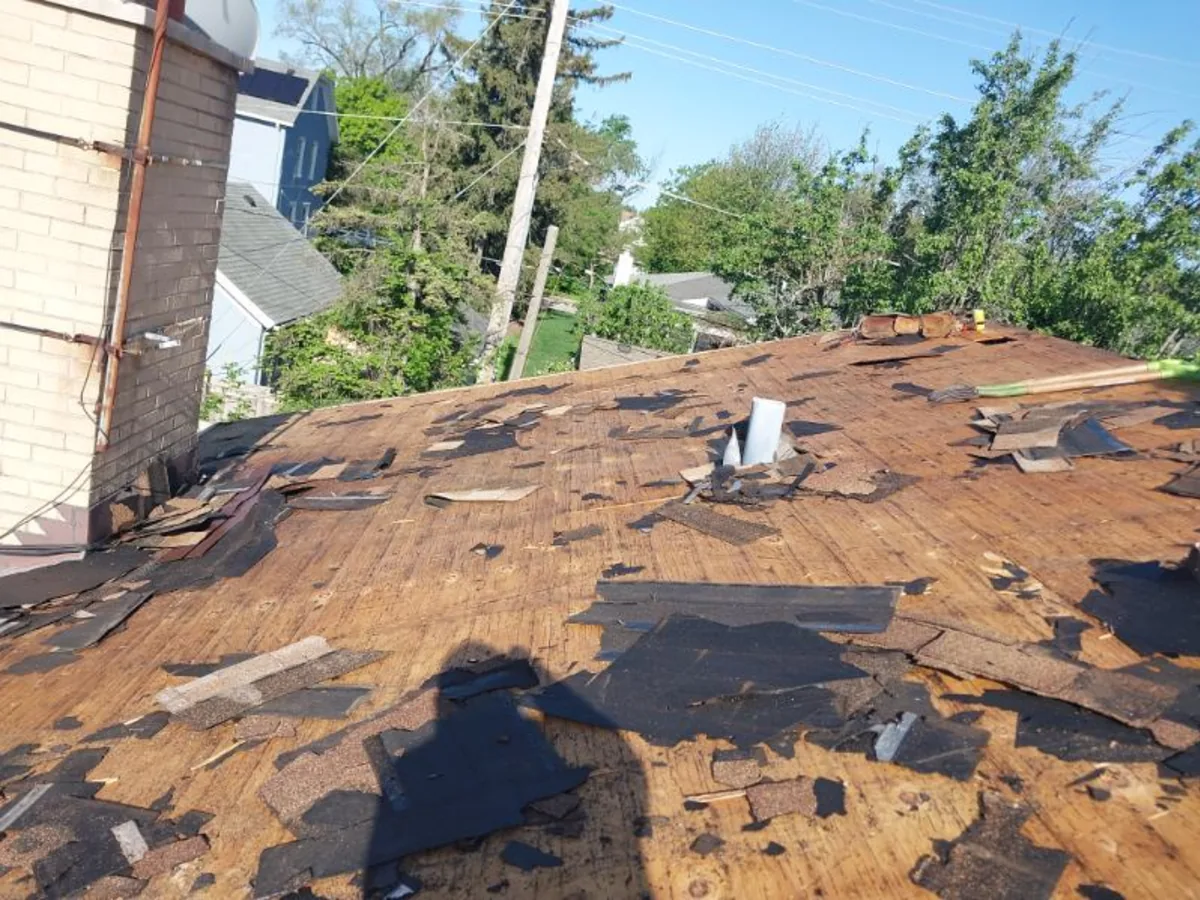 Residential roof tear off in progress with ladder access