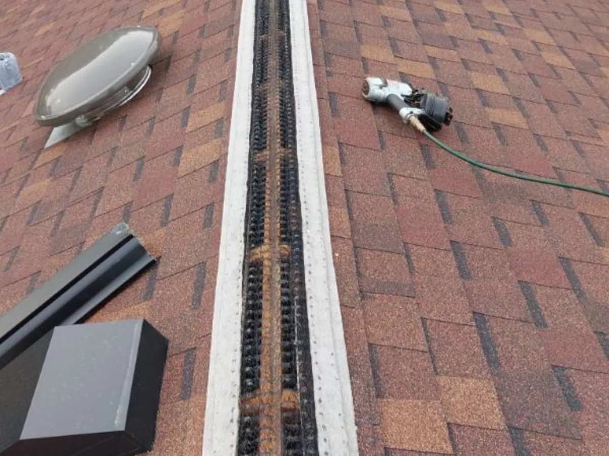 Ridge vent slot cut into a brown asphalt shingle roof