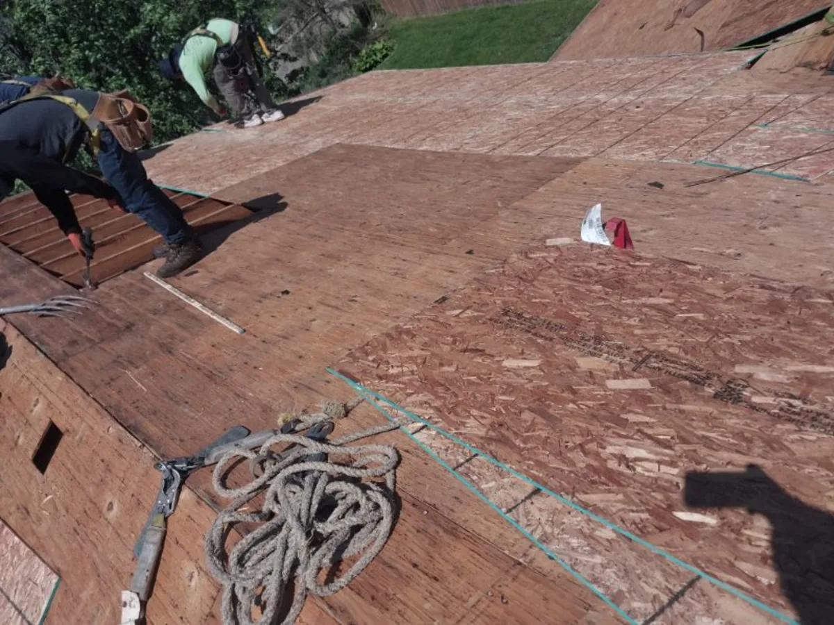 Roofer tearing off old shingles down to the wood deck